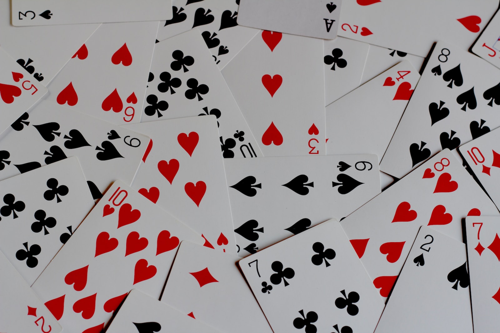 a pile of playing cards with hearts and spades